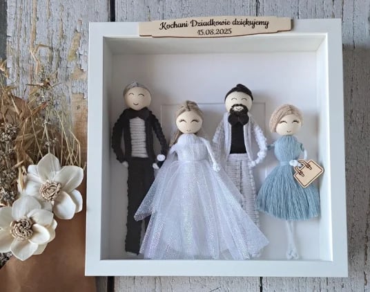 Shadow box z czterema laleczkami w ślubnych kreacjach oraz spersonalizowaną tabliczką z imionami, udekorowany suszonymi kwiatami